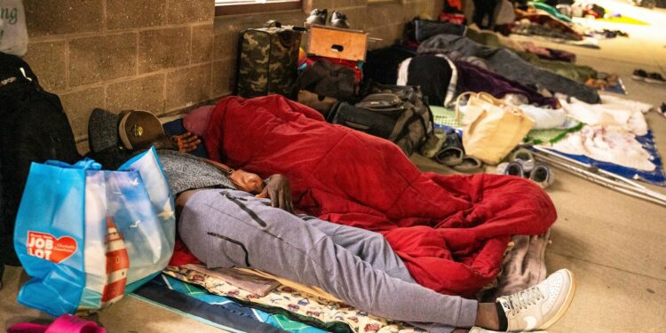 Odrick Dorcias, 28, a Haitian migrant, prepared to stay overnight with others outside the Wollaston T stop on Aug. 26.