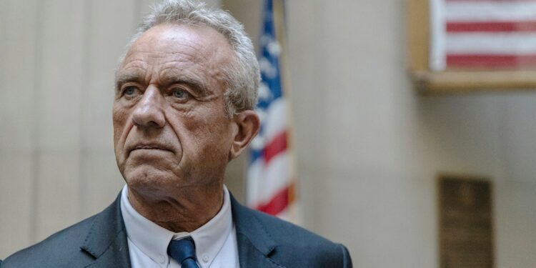 RFK Jr standing in front of an American flag