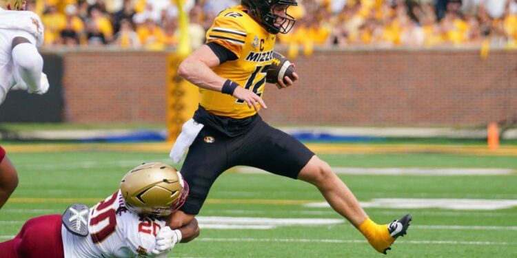 Sep 14, 2024; Columbia, Missouri, USA; Missouri Tigers quarterback Brady Cook (12) runs the ball as Boston College Eagles defensive back KP Price (20) makes the tackle during the first half at Faurot Field at Memorial Stadium. Mandatory Credit: Denny Medley-Imagn Images