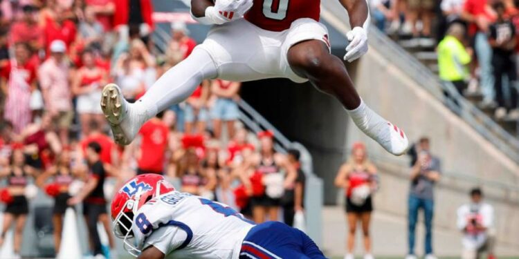 N.C. State running back Kendrick Raphael (0) hurdles over Louisiana Tech defensive back Demarcus Griffin-Taylor (8) during the first half of N.C. State’s game against LA Tech at Carter-Finley Stadium in Raleigh, N.C., Saturday, Sept. 14, 2024.