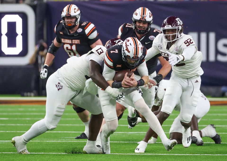 Dec 27, 2023; Houston, TX, USA; Oklahoma State Cowboys quarterback Alan Bowman (7) is tackled by Texas A&M Aggies defensive lineman DJ Hicks (13) in the second quarter at NRG Stadium. Mandatory Credit: Thomas Shea-USA TODAY Sports