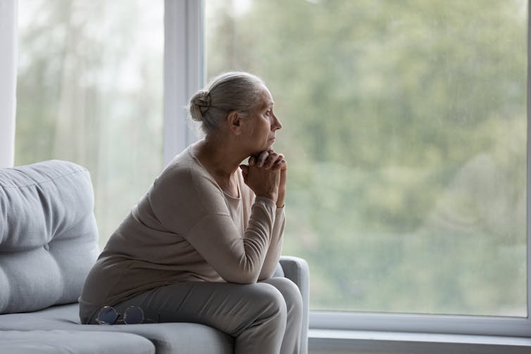 A senior woman pensively looking out a window.