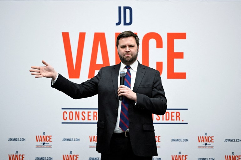 JD Vance campaigns in front of a sign that has his name and the words 