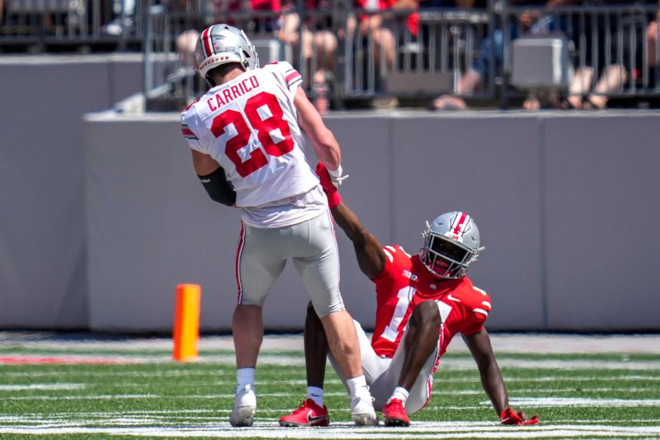 Apr 15, 2023; Columbus, Ohio, United States;  Ohio State Buckeyes linebacker Reid Carrico (28) helps Ohio State Buckeyes wide receiver Kojo Antwi (14) stand up off the ground during the second quarter of the Ohio State Buckeyes spring game at Ohio Stadium on Saturday morning. Mandatory Credit: Joseph Scheller-The Columbus Dispatch