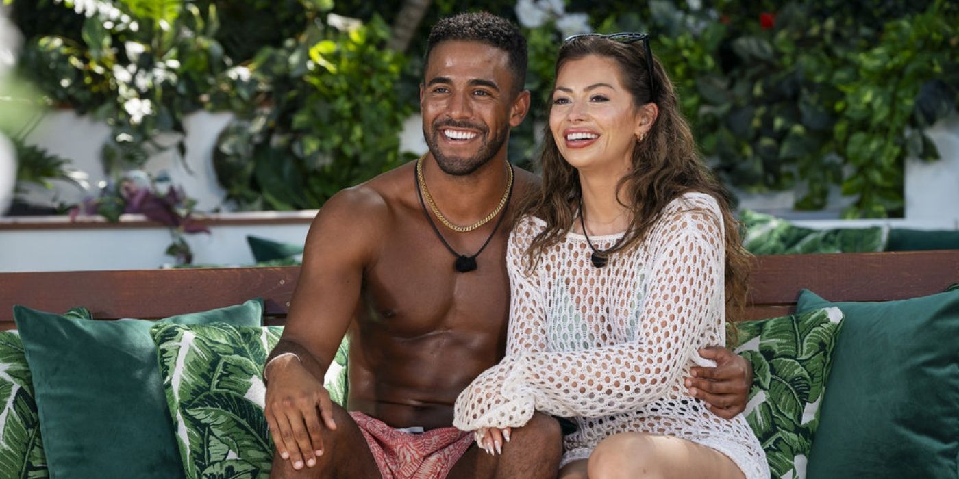 Kendall Washington wears swim trunks sitting next to Nicole Jacky in a swimsuit and white cover up on 'Love Island USA' 