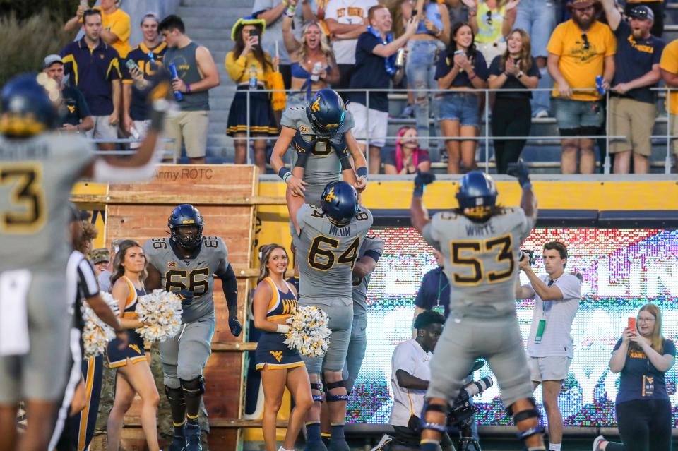 Sep 11, 2021; Morgantown, West Virginia, USA; West Virginia Mountaineers quarterback Garrett Greene (6) celebrates with West Virginia Mountaineers offensive lineman Wyatt Milum (64) after a touchdown during the third quarter against the Long Island Sharks at Mountaineer Field at Milan Puskar Stadium. Mandatory Credit: Ben Queen-USA TODAY Sports