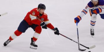 Jun 24, 2024; Sunrise, Florida, USA; Florida Panthers forward Anton Lundell (15) and Edmonton Oilers defenseman Philip Broberg (86) reach for the puck during the second period in game seven of the 2024 Stanley Cup Final at Amerant Bank Arena. Mandatory Credit: Sam Navarro-USA TODAY Sports