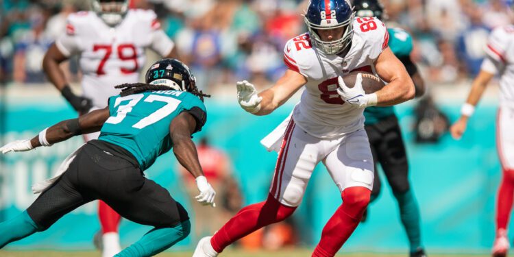 Oct 23, 2022; Jacksonville, Florida, USA;  New York Giants tight end Daniel Bellinger (82) catches the ball against Jacksonville Jaguars cornerback Tre Herndon (37) in the second quarter at TIAA Bank Field. Mandatory Credit: Jeremy Reper-USA TODAY Sports