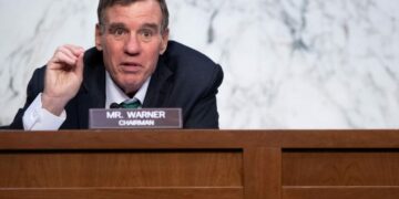 Mark Warner in front of sign saying Chairman Mr. Warner