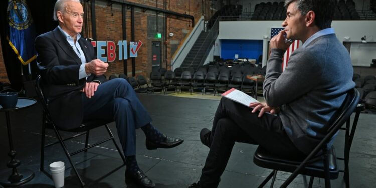 Joe Biden and George Stephanopoulos facing each other in an interview. Both men are dressed semi-casually