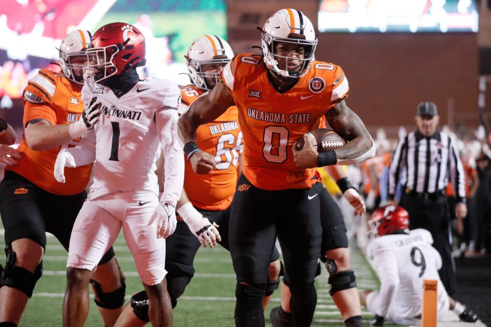 Oct 28, 2023; Stillwater, Oklahoma, USA; Oklahoma State Cowboys running back Ollie Gordon II (0) celebrstes beside Cincinnati Bearcats cornerback Jordan Young (1) after running for a touchdown the third quarter of a college football game between Oklahoma State and Cincinnati at Boone Pickens Stadium. Oklahoma State won 45-13. Mandatory Credit: Bryan Terry-USA TODAY Sports