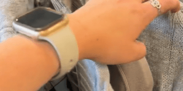 A woman's hand flipping through a clothing rack.