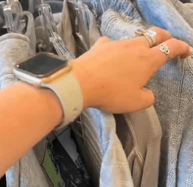 A woman's hand flipping through a clothing rack.