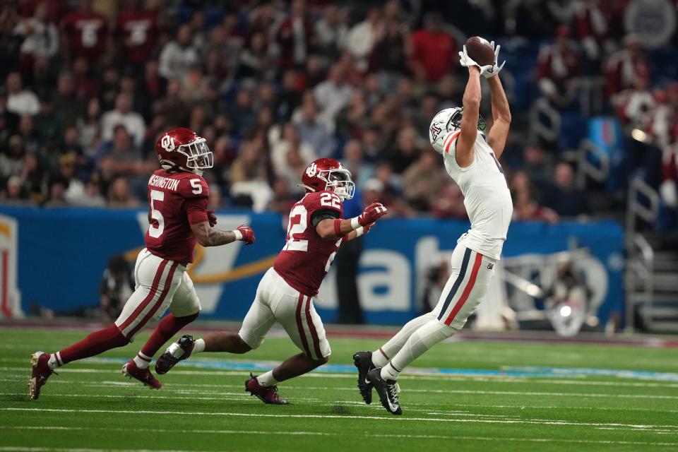 Dec 28, 2023; San Antonio, TX, USA; Arizona Wildcats wide receiver Tetairoa McMillan (4) catches the ball against Oklahoma Sooners defensive back Woodi Washington (5) and defensive back Peyton Bowen (22) in the fist half of the Alamo Bowl at Alamodome. Mandatory Credit: Kirby Lee-USA TODAY Sports