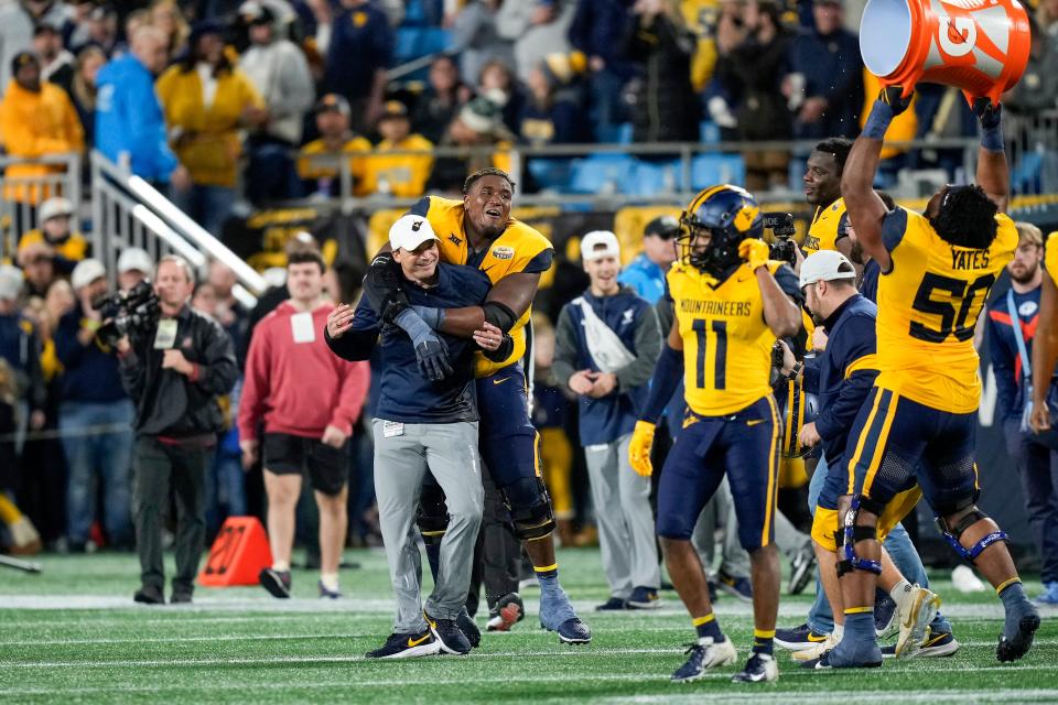 Dec 27, 2023; Charlotte, NC, USA; West Virginia Mountaineers head coach Neal Brown celebrates with his team after the win over North Carolina Tar Heels during the second half at Bank of America Stadium. Mandatory Credit: Jim Dedmon-USA TODAY Sports