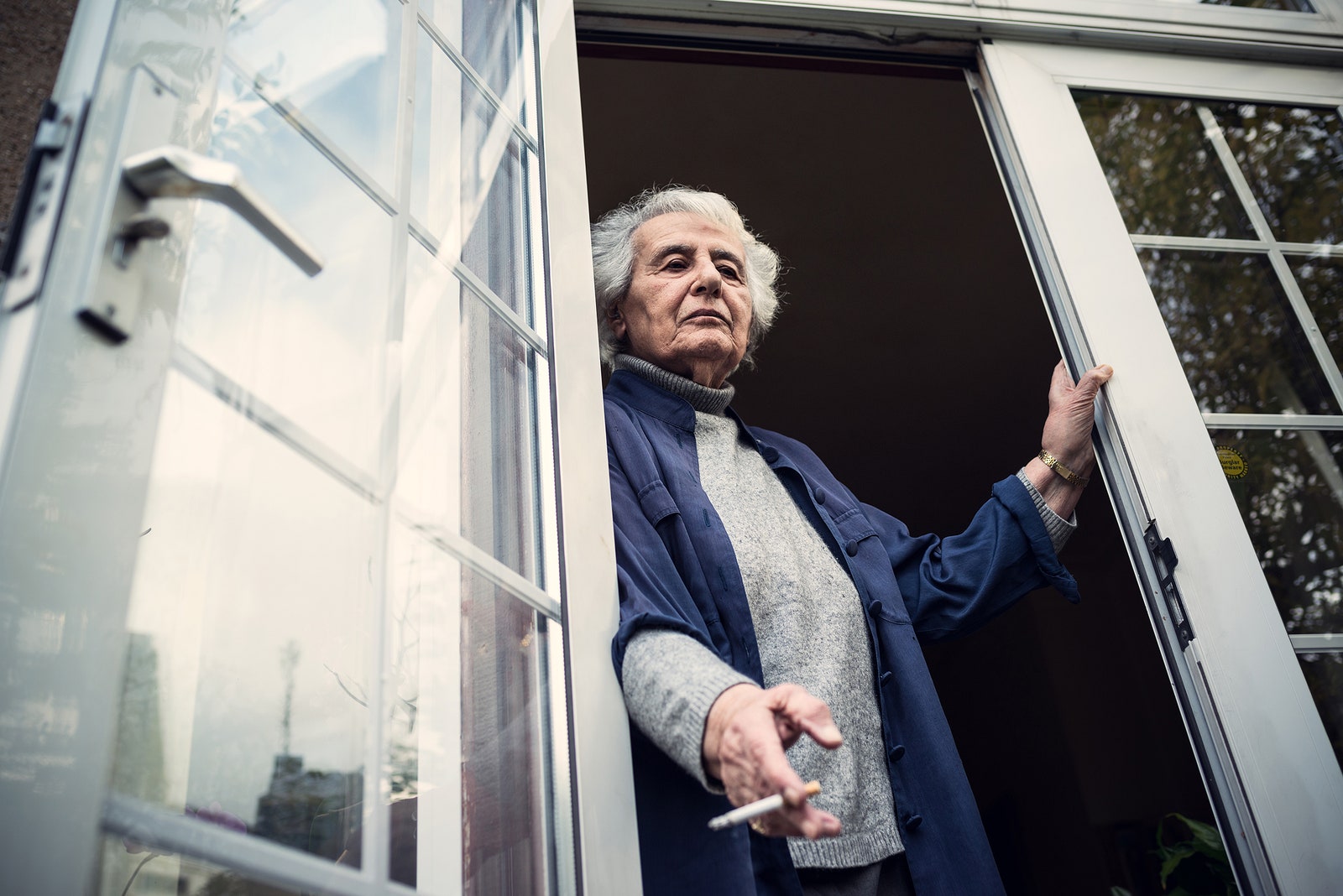 Anita LaskerWallfisch standing at a balcony with cigarette in hand.