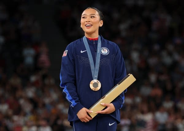 a gymnast poses with a medal