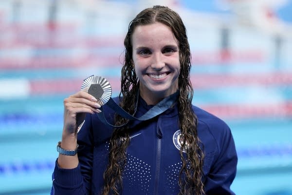 a swimmer poses with a medal