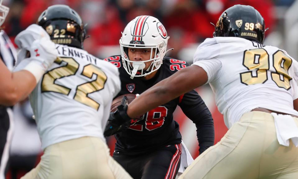 SALT LAKE CITY, UT - NOVEMBER 25: Sione Vaki #28 of the Utah Utes rushes the ball agaisnt Demouy Kennedy#22 and Shane Cokes #99 of the Colorado Buffaloes during the second half of their game at Rice Eccles Stadium on November 25, 2023 in Salt Lake City, Utah. (Photo by Chris Gardner/Getty Images)