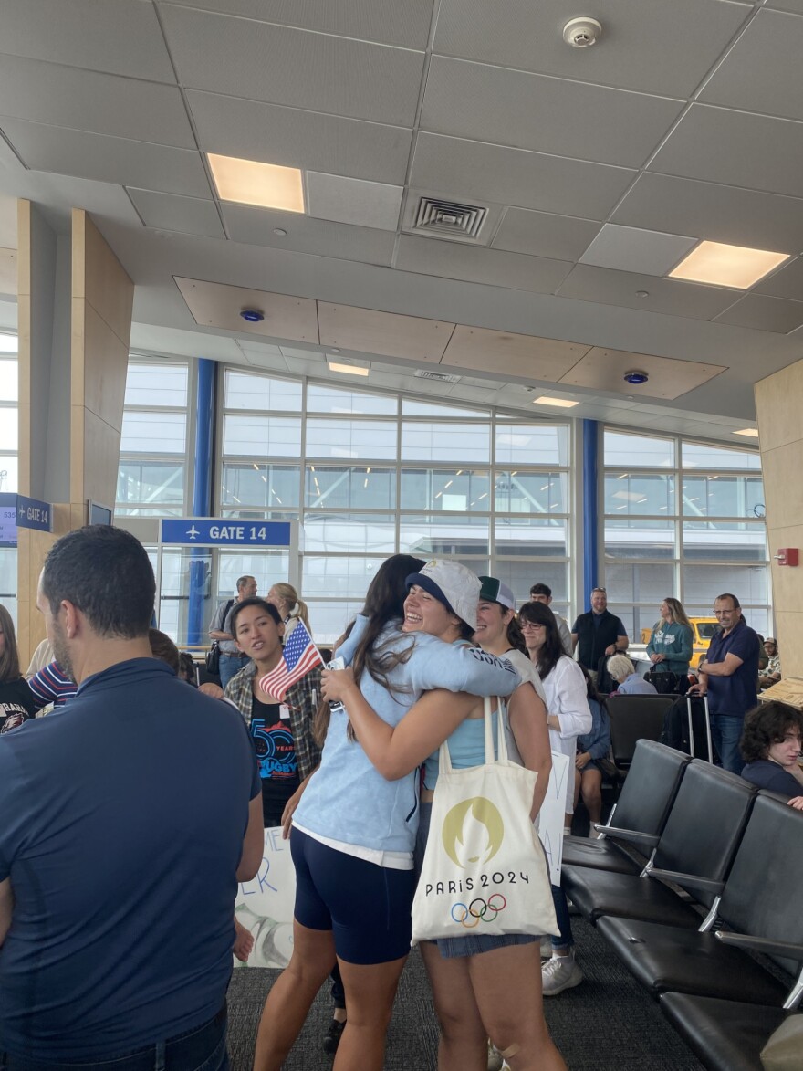 Ilona Maher embraces members of the UVM women's rugby team and the Burlington women's club team in the airport terminal 