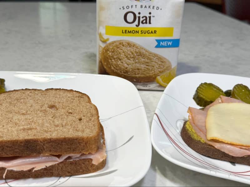 Sandwiches with cold cuts and cheese with pickles, and bag of lemon sugar cookies