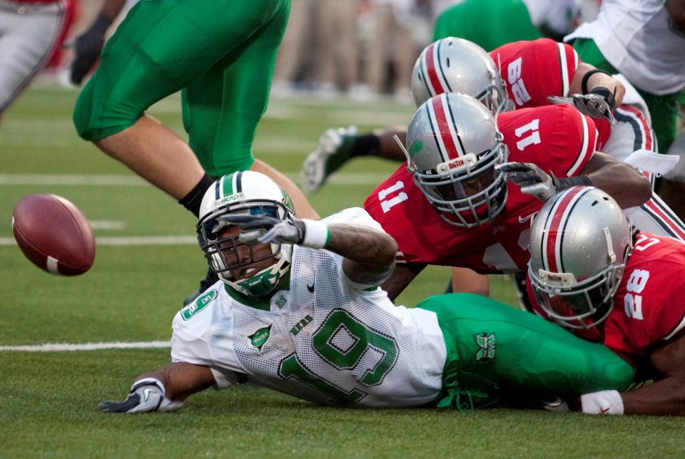 Sept 2, 2010; Columbus, OH, USA; Marshall Thundering Herd running back Andre Booker (19) fumbles while being tackled by Ohio State Buckeyes defensive back Dominic Clarke (28) and linebacker Dorian Bell (11) on the opening play of their game at Ohio Stadium. Greg Bartram-USA TODAY Sports