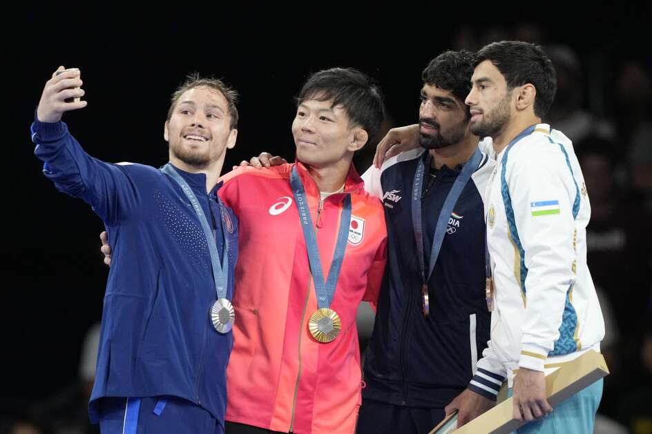 Medalists, from left, Spencer Lee, of the United States, silver, Japan's Rei Higuchi, gold, India's Aman Aman, Uzbekistan's Gulomjon Abdullaev, bronze, take a selfie on the podium during the medal ceremony for men's freestyle 57kg wrestling, at Champ-de-Mars Arena, during the 2024 Summer Olympics, Friday, Aug. 9, 2024, in Paris, France. (AP Photo/Eugene Hoshiko)