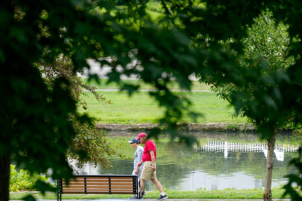 A group of people walking beside Hughes Lake at Third Ward Park in Passaic on July 24, 2024.