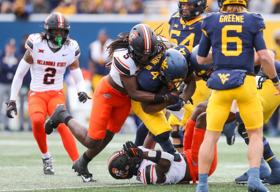 Oct 21, 2023; Morgantown, West Virginia, USA; Oklahoma State Cowboys safety Kendal Daniels (5) tackles West Virginia Mountaineers running back CJ Donaldson Jr. (4) during the first quarter at Mountaineer Field at Milan Puskar Stadium. Mandatory Credit: Ben Queen-USA TODAY Sports