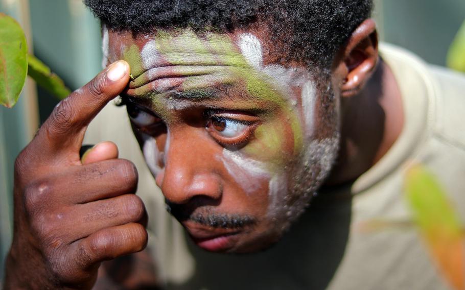 U.S. Army Pfc. Dewayne Johnson, a cavalry scout assigned to 3rd Squadron, 4th Cavalry Regiment, 3rd Infantry Brigade Combat Team, 25th Infantry Division, applies face paint during an exercise at Helemano Military Reservation, Hawaii, Nov. 2, 2023.