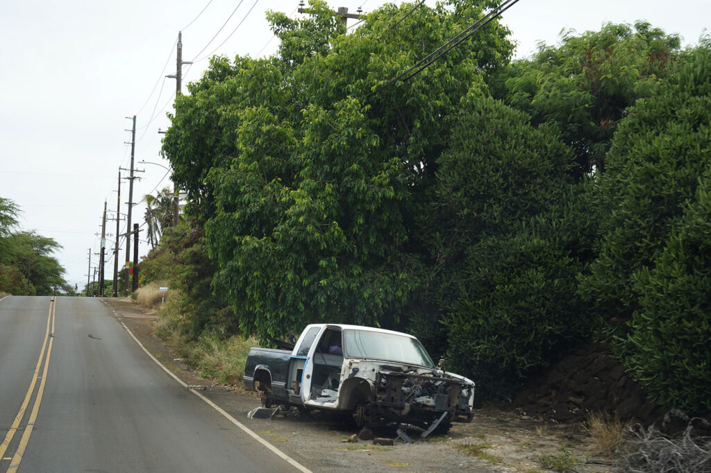 An abandoned pickup truck litters Waianae Valley Road Tuesday, July 30, 2024, in Waianae. These locations show areas prone to wildfire, structure fires and mitigation attempts. (Kevin Fujii/Civil Beat/2024)