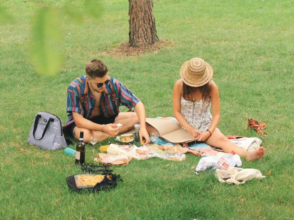 A girl and a boy have a picnic in a park in Prague.