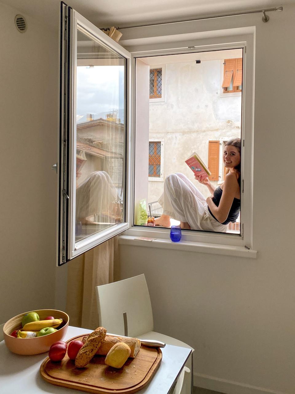 Girl sits by the window with her book in Italy