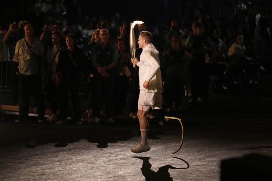 Germany's Markus Rehm holds the Paralympic flame during the torch relay as part of the Paris 2024 Paralympic Games Opening Ceremony in Paris on August 28, 2024.