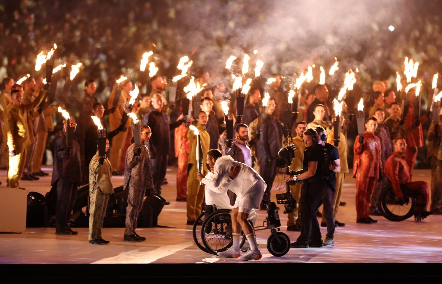 Performers hold flames whilst the torchbearers exchange the Paralympic Flame during the opening ceremony.