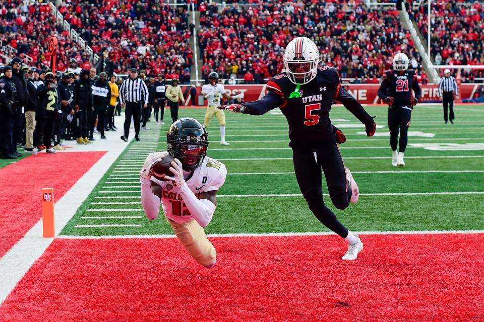 Nov 25, 2023; Salt Lake City, Utah, USA; Colorado Buffaloes athlete Travis Hunter (12) dives for a catch in the end zone in front of Utah Utes cornerback Zemaiah Vaughn (5) at Rice-Eccles Stadium. Mandatory Credit: Christopher Creveling-USA TODAY Sports