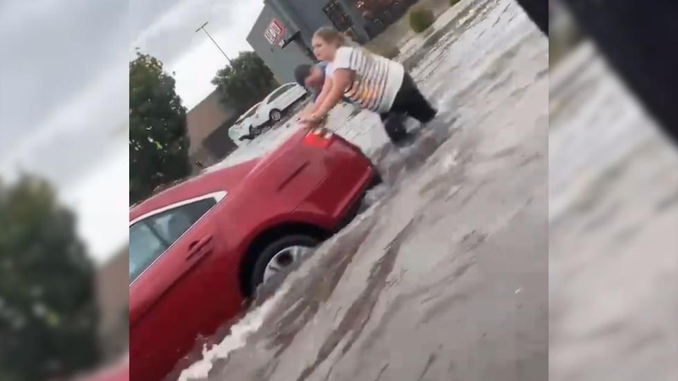 Chick-fil-A managers Sammi Young and Jarret Hartley help push stalled cars in the Chick-fil-A...