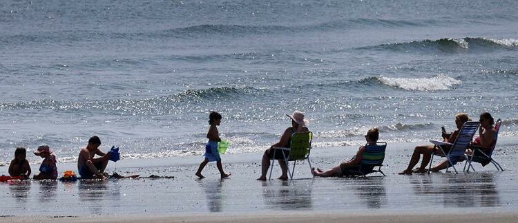 A family enjoys the sun, the sand and the sounds of the surf at Nantasket Beach.