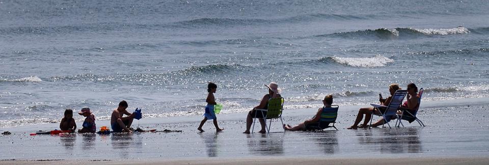 A family enjoys the sun, the sand and the sounds of the surf at Nantasket Beach.