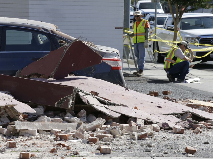 City workers at right map out the installation of fencing around earthquake damaged buildings Tuesday, Aug. 26, 2014, in Napa, Calif. 