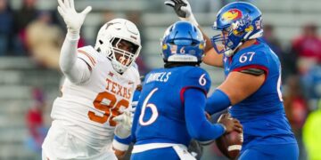 Nov 19, 2022; Lawrence, Kansas, USA; Texas Longhorns defensive lineman Moro Ojomo (98) rushes Kansas Jayhawks quarterback Jalon Daniels (6) as offensive lineman Dominick Puni (67) blocks during the second half at David Booth Kansas Memorial Stadium. Mandatory Credit: Jay Biggerstaff-USA TODAY Sports