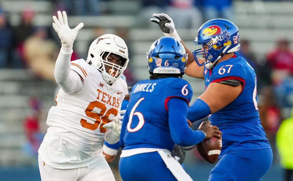 Nov 19, 2022; Lawrence, Kansas, USA; Texas Longhorns defensive lineman Moro Ojomo (98) rushes Kansas Jayhawks quarterback Jalon Daniels (6) as offensive lineman Dominick Puni (67) blocks during the second half at David Booth Kansas Memorial Stadium. Mandatory Credit: Jay Biggerstaff-USA TODAY Sports