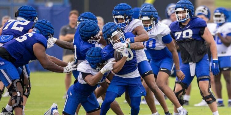 Running back Jamarion Wilcox pushes past defenders during Kentucky fan day practice on Saturday.