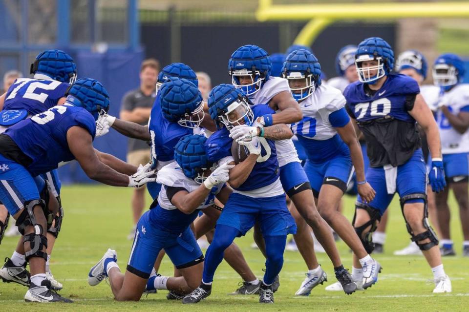 Running back Jamarion Wilcox pushes past defenders during Kentucky fan day practice on Saturday.