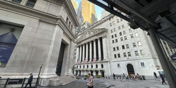 People pass the New York Stock Exchange, at rear, on Tuesday, Aug. 27, 2024, in New York.