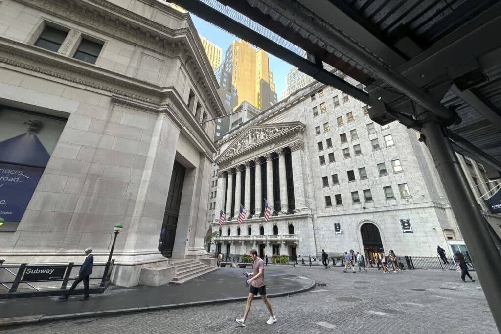 People pass the New York Stock Exchange, at rear, on Tuesday, Aug. 27, 2024, in New York.