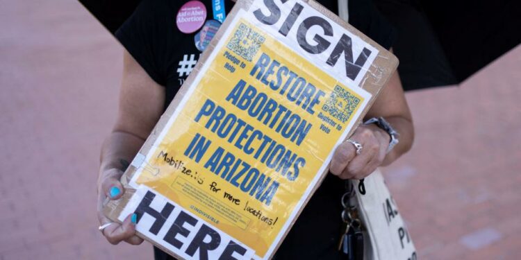 An organizer carries a clipboard with petitions for a ballot initiative to enshrine abortion into the Arizona state constitution in Tucson, Arizona, on April 9, 2024.