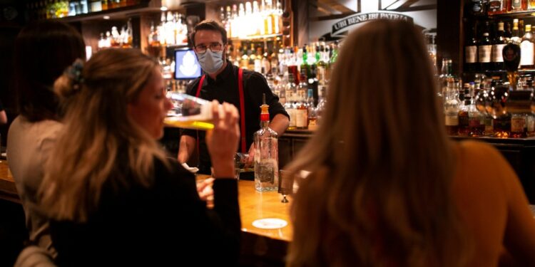 Patrons ordering drinks in a Montreal pub before closure due to COVID-19 regulations