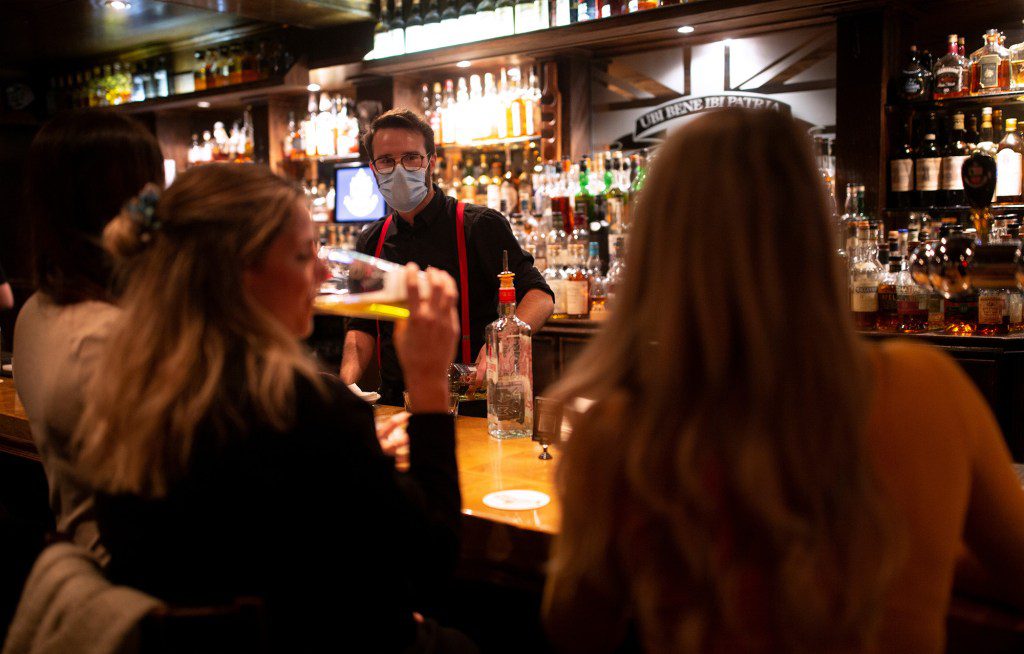 Patrons ordering drinks in a Montreal pub before closure due to COVID-19 regulations