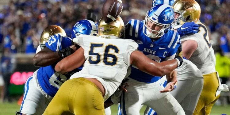 Sep 30, 2023; Durham, North Carolina, USA; Duke Blue Devils quarterback Riley Leonard (13) loses the football near the goal line hit by Notre Dame Fighting Irish defensive lineman Howard Cross III (56) during the second quarter at Wallace Wade Stadium. Mandatory Credit: Jim Dedmon-USA TODAY Sports